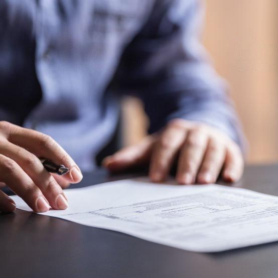 Pessoa sentada a assinar um contrato de trabalho com uma caneta.