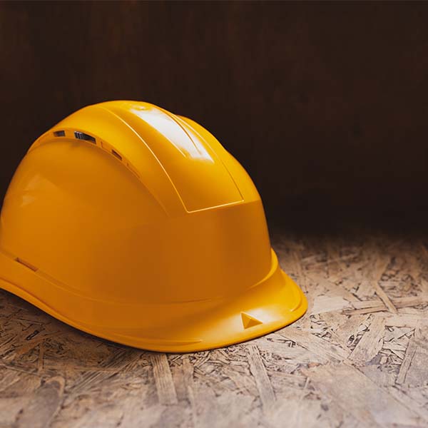 Capacete amarelo em madeira, representando contrato de empreitada com advogado.