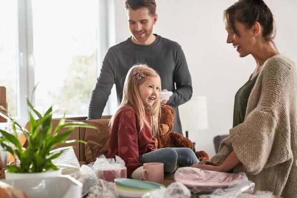 Família sorridente a desfazer as malas em casa, representando serviço de advogado de família