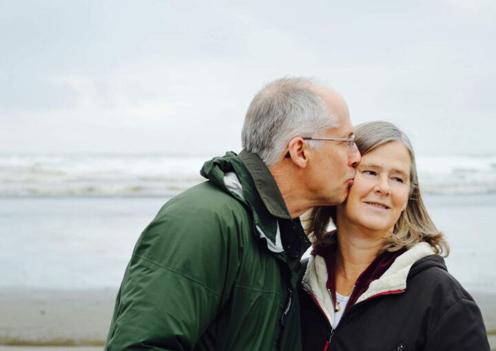 pessoa idoso a beijar outra pessoa idosa na praia representadno o cabeça de casal