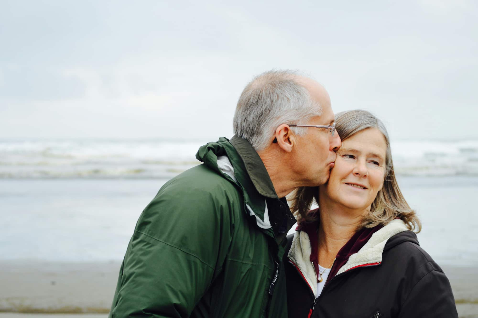 pessoa idoso a beijar outra pessoa idosa na praia representadno o cabeça de casal