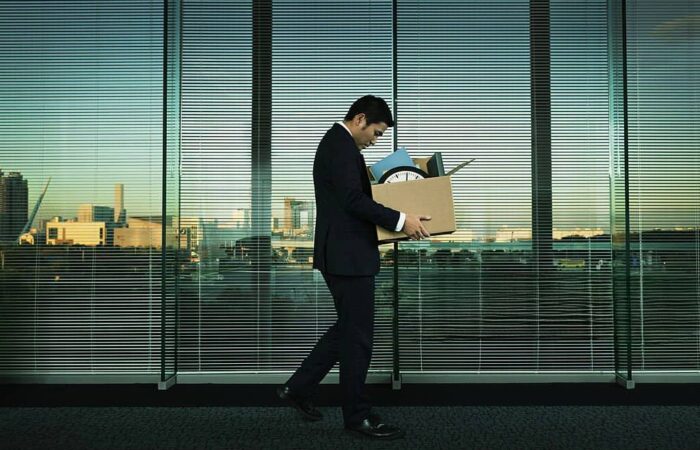 trabalhador despedido por justa causa a sair do escritório com a caixa na mão.
