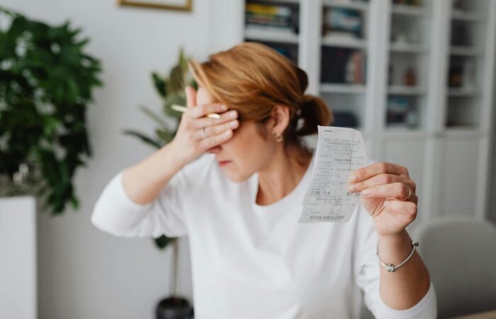 Mãe com a mão na cara ao ver que o pai não pagou a pensão de alimentos.