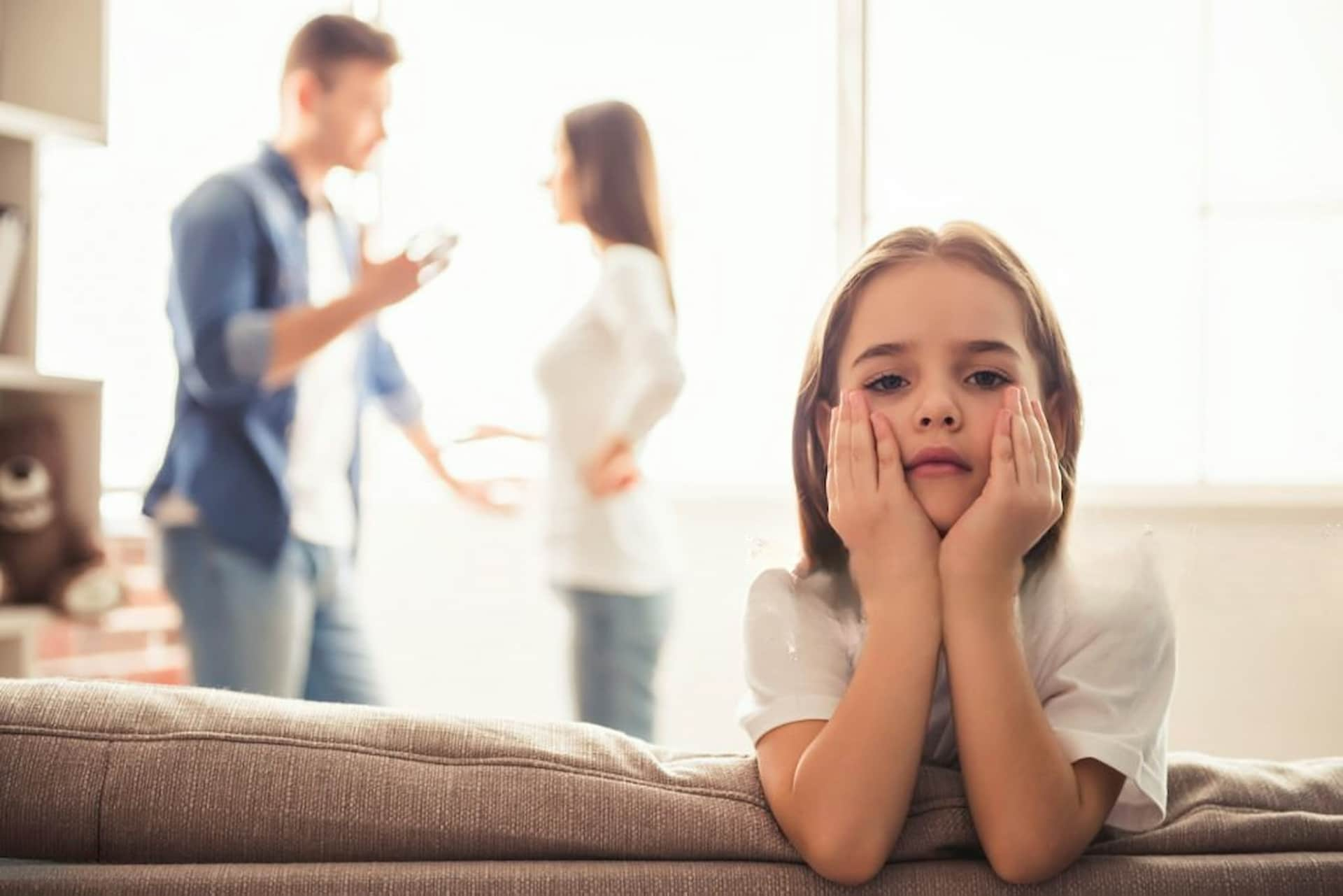 Pai discute com a mãe sobre a pensão de alimentos enquanto a filha está aborrecida.