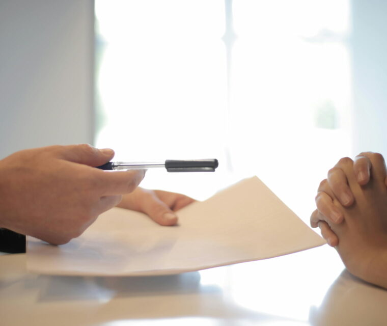 Advogado comercial segura uma caneta e um contrato em frente ao cliente