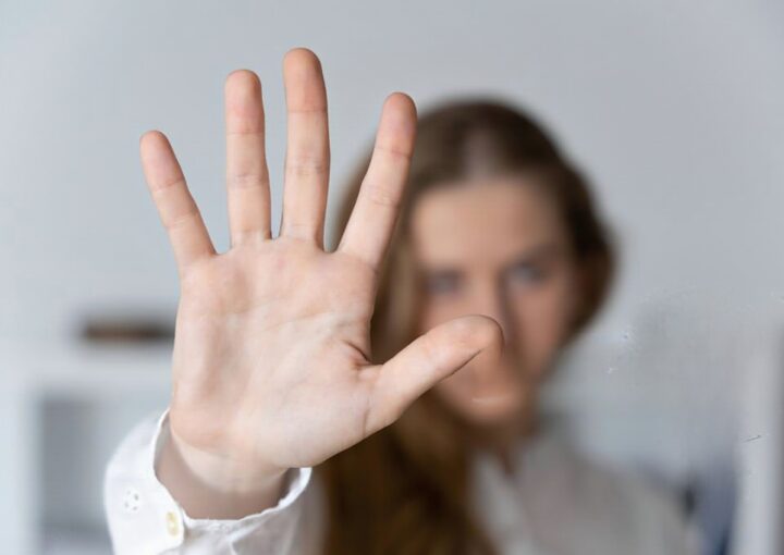 Mulher com a mão levantada como forma de denunciar violência domestica.