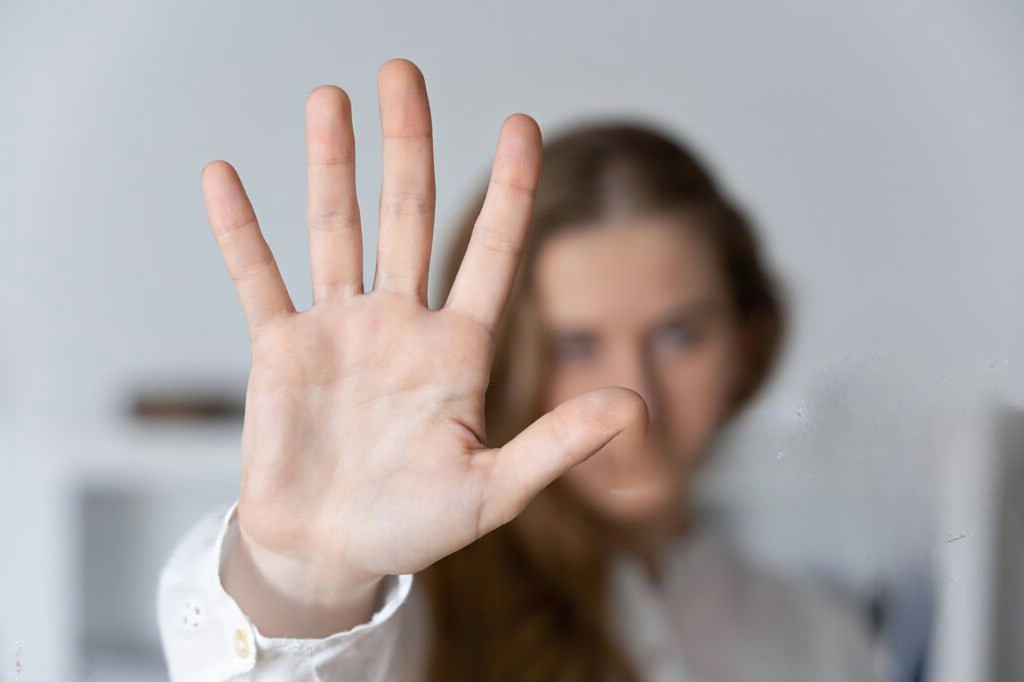 Mulher com a mão levantada como forma de denunciar violência domestica.