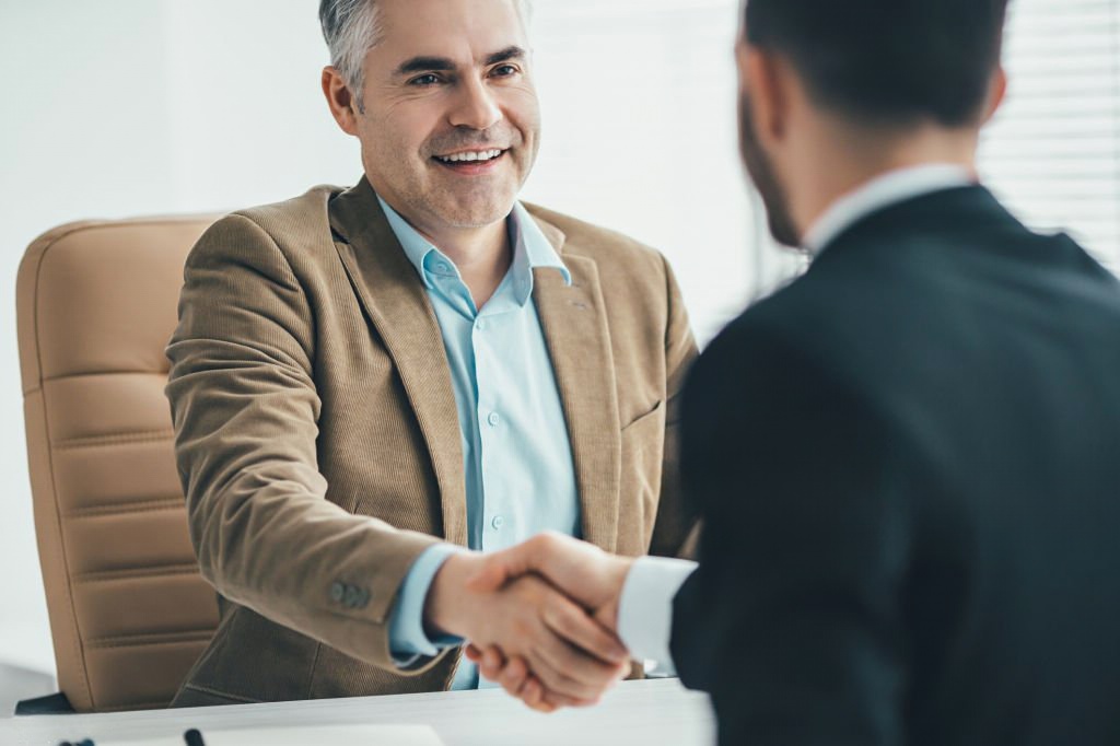 Duas pessoas a apertão a mão como forma de acordo de contrato de trabalho