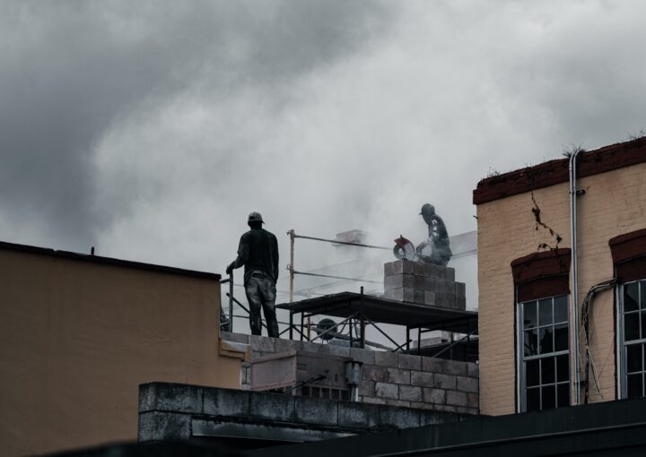 dois trabalhadores em cima de um andaime numa obra.