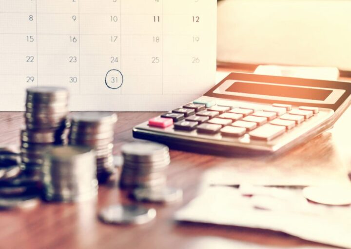 calendario com data agendada, uma calculadora e moedas como forma de simbolizar uma divida a ser paga