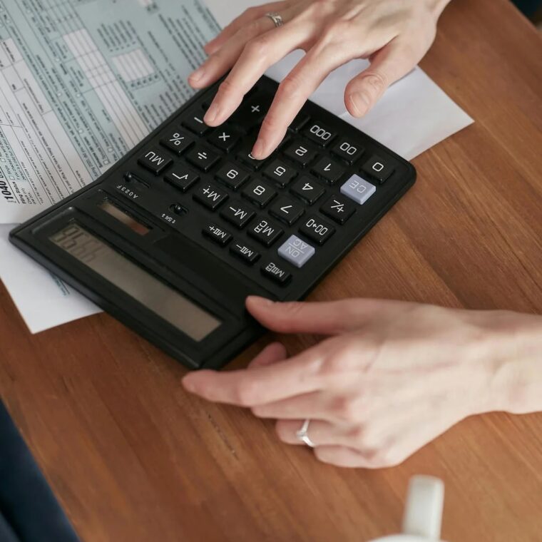 duas mãos na calculadora a fazer o calculo das dívidas as finanças