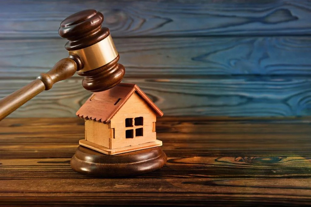 Casa e martelo da justiça a simbolizar um processo de usucapião de imóvel