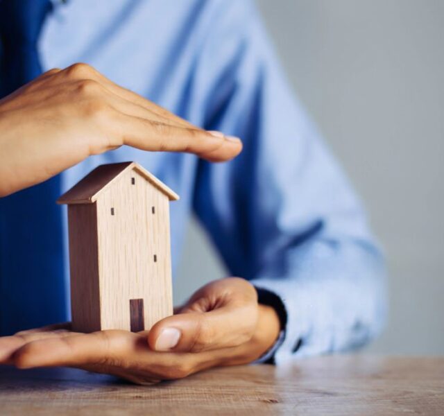 duas mão a segurar uma casa a simbolizar um seguro de habitação