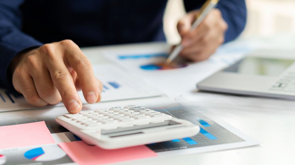 Pessoa a fazer contas com calculadora às dívidas à segurança social