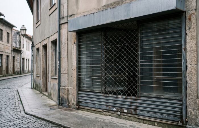 Montra de loja fechada com grade descida, vista da rua