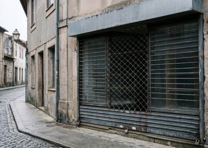 Montra de loja fechada com grade descida, vista da rua
