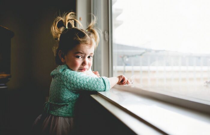 Criança triste a olhar pela janela a espera do pai