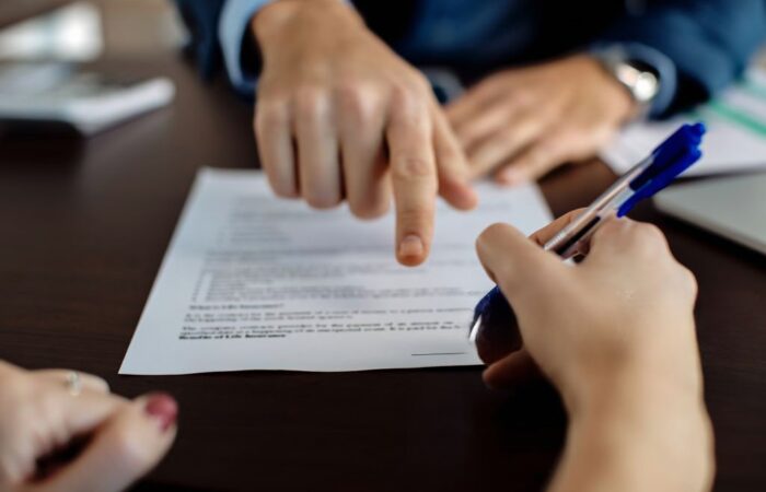 Advogado apontar para o documento enquanto outra pessoa assina a reclamação graciosa