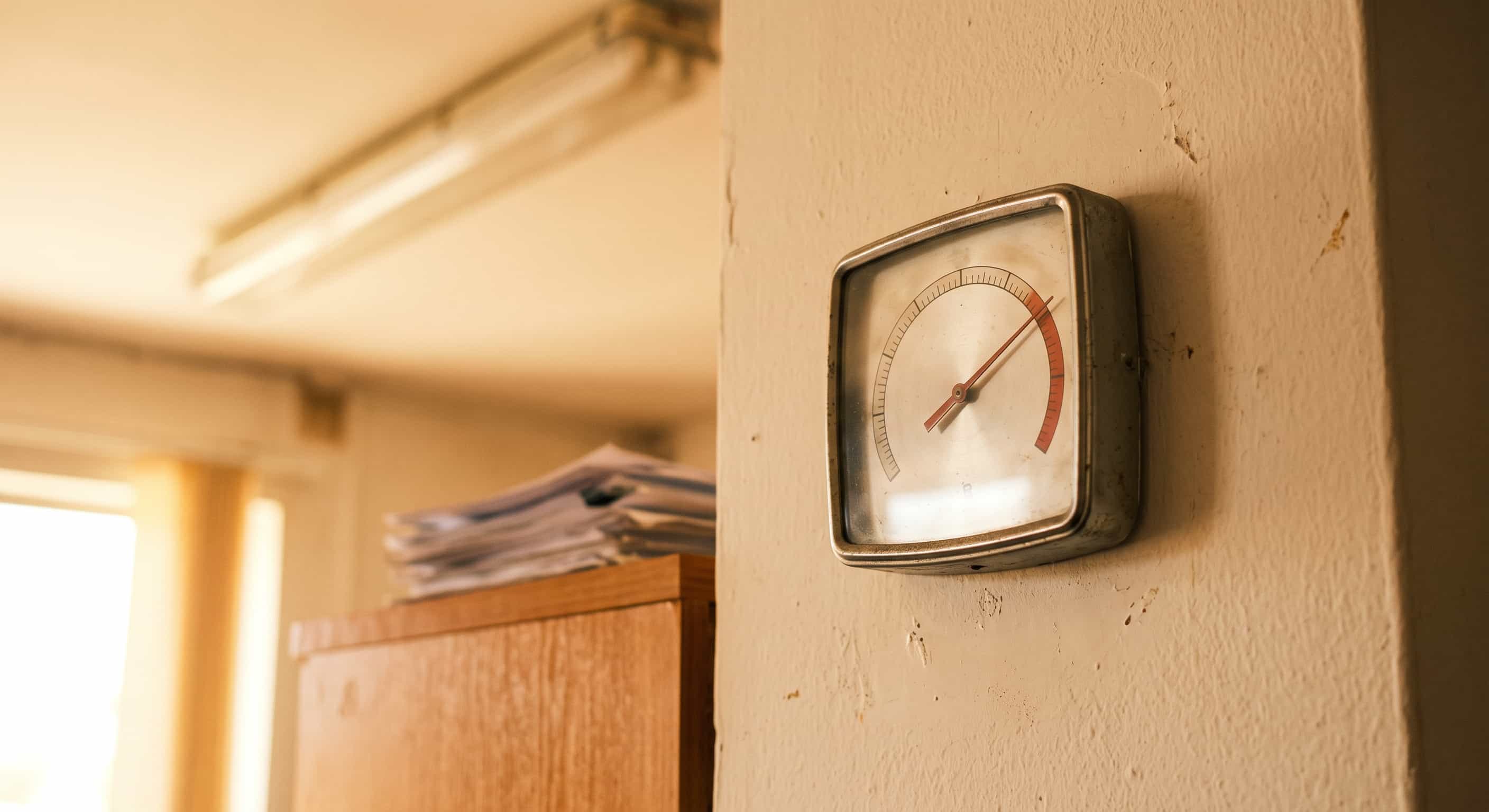 Termómetro numa parede de escritório a marcar temperatura elevada durante o horário de trabalho