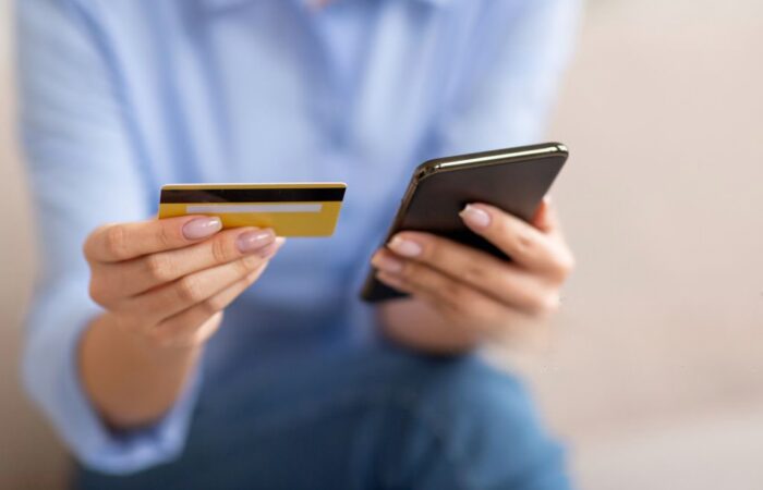 Mulher com o cartão de crédito e um telefone nas mãos a simbolizar uma burla informática