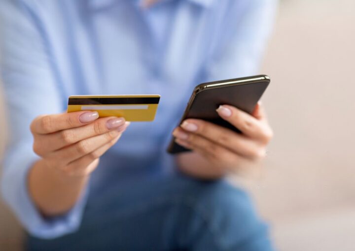 Mulher com o cartão de crédito e um telefone nas mãos a simbolizar uma burla informática