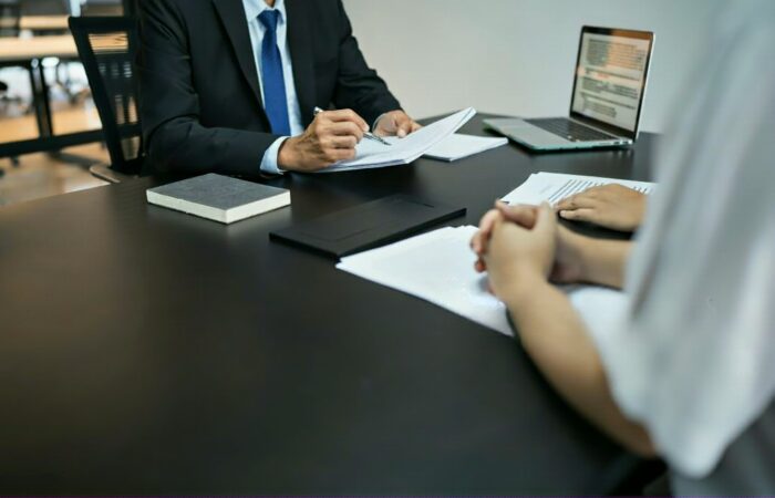 Advogado a rever documentos com um cliente numa reunião, possivelmente sobre despedimento urgente, ilustrando a busca por apoio jurídico.