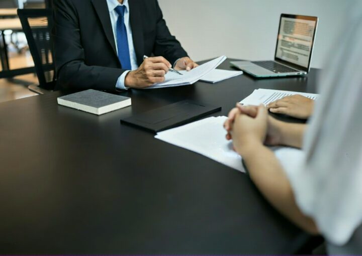 Advogado a rever documentos com um cliente numa reunião, possivelmente sobre despedimento urgente, ilustrando a busca por apoio jurídico.