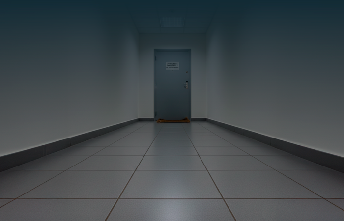 Porta de apartamento fechada num prédio residencial, com um aviso em papel afixado ao centro e um tapete gasto no chão do corredor.