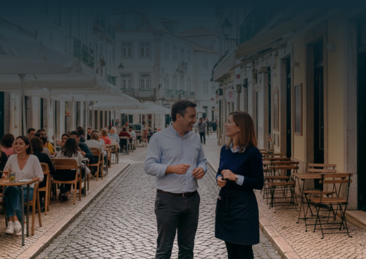 Uma rua pedonal em Portugal com duas situações distintas: à esquerda, uma esplanada completa com guarda-sóis e clientes, e à direita, mesas simples junto à fachada, representando a diferença entre licenciamento obrigatório e dispensado.