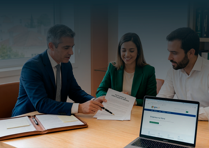 Fotografia de um advogado de fato explicando os documentos de constituição de empresa (Pacto Social) a dois empreendedores num escritório moderno com luz natural.