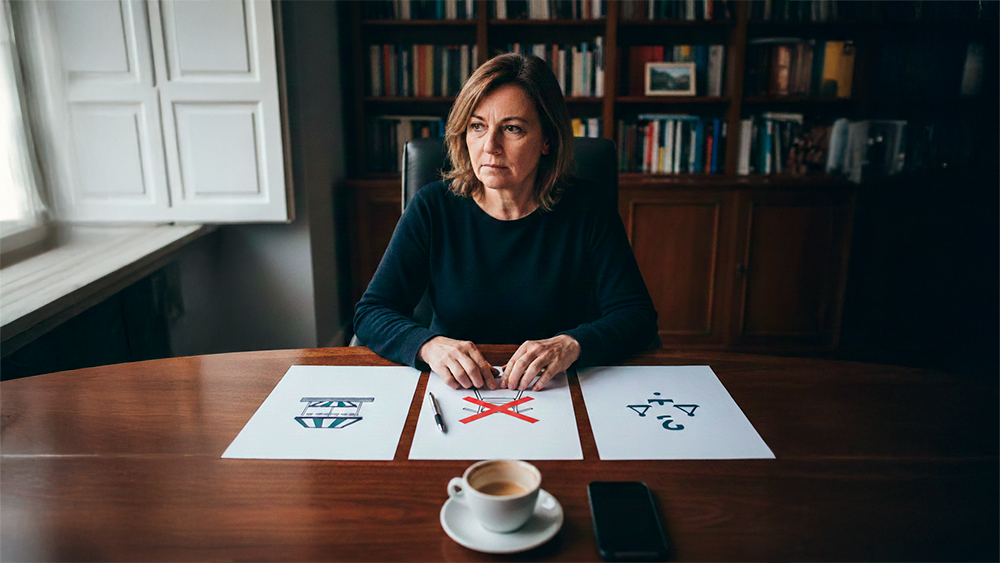 Uma mulher sentada à mesa de um escritório, em tom reflexivo, com três folhas de papel à sua frente exibindo ícones que representam a legalização, a remoção e a contestação jurídica de uma esplanada.