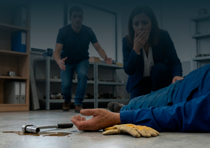 Colegas de trabalho assustados e preocupados aproximam-se de trabalhador acidentado no chão, simbolizando o momento de um acidente de trabalho.