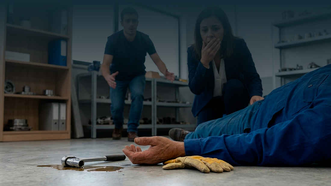 Colegas de trabalho assustados e preocupados aproximam-se de trabalhador acidentado no chão, simbolizando o momento de um acidente de trabalho.