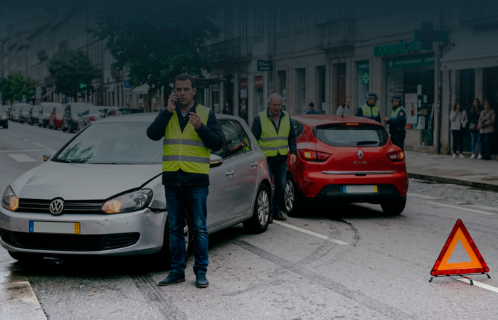 Condutores com coletes refletores após acidente de viação a sinalizar a estrada e a pedir assistência.