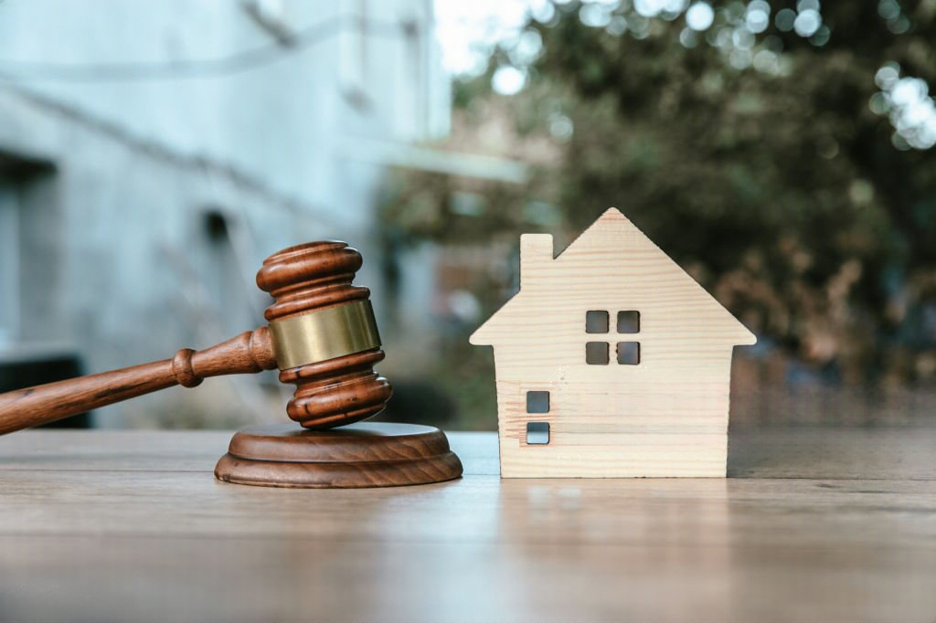 "Martelo de juiz e pequena casa de madeira sobre uma mesa, a ilustrar os processos legais da usucapião de imóveis."