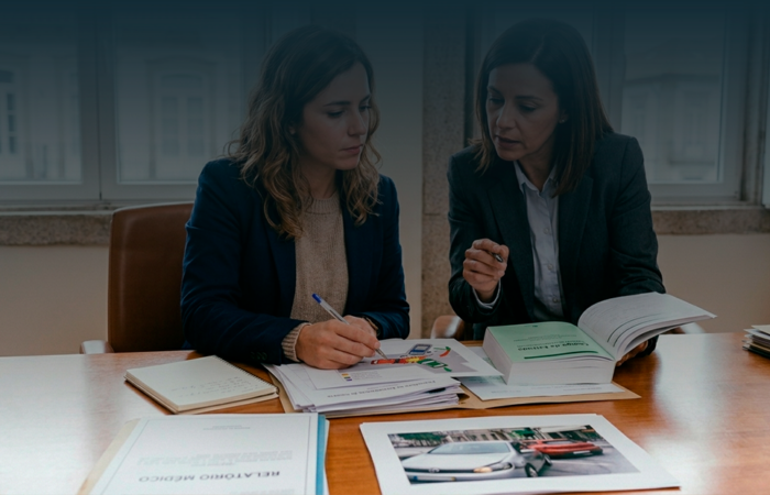 Mulher em reunião num escritório a analisar provas de acidente de viação e relatórios médicos para pedido de indemnização.