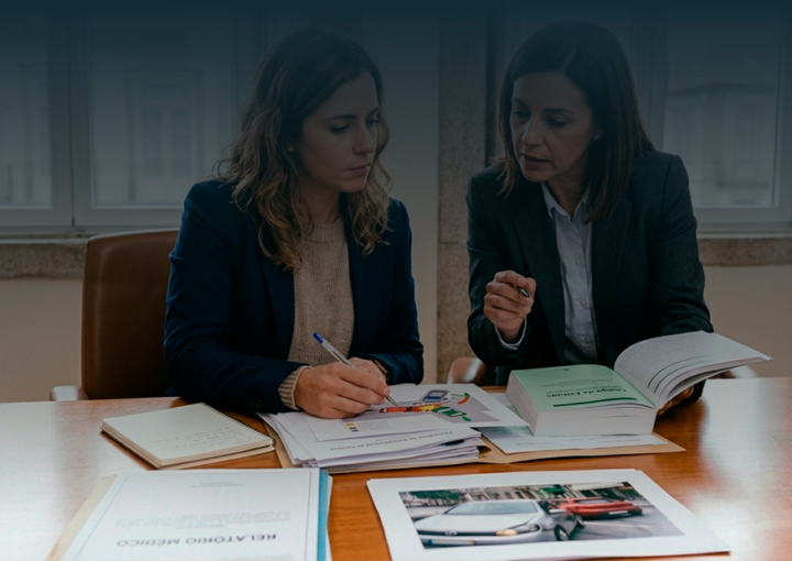 Mulher em reunião num escritório a analisar provas de acidente de viação e relatórios médicos para pedido de indemnização.