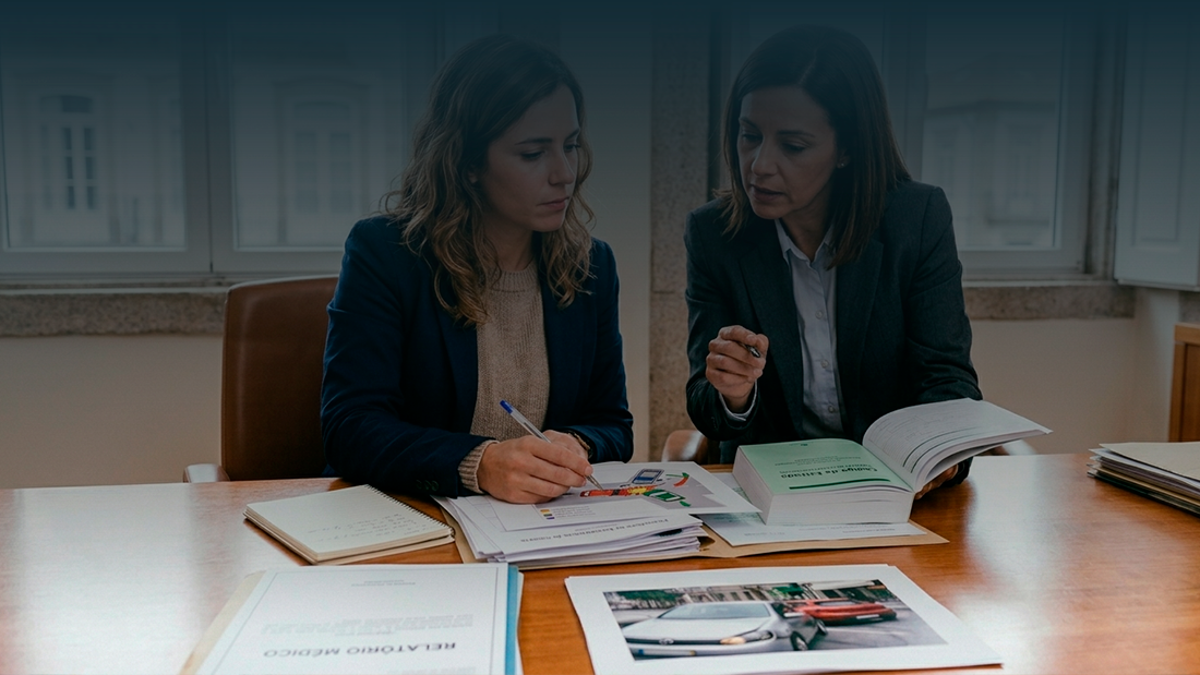 Mulher em reunião num escritório a analisar provas de acidente de viação e relatórios médicos para pedido de indemnização.