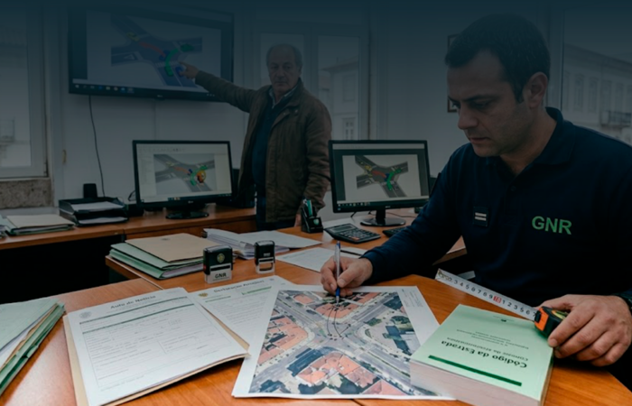 Agente da GNR e especialista a analisar fotografias de danos, mapas e auto de notícia para determinar a responsabilidade no acidente.