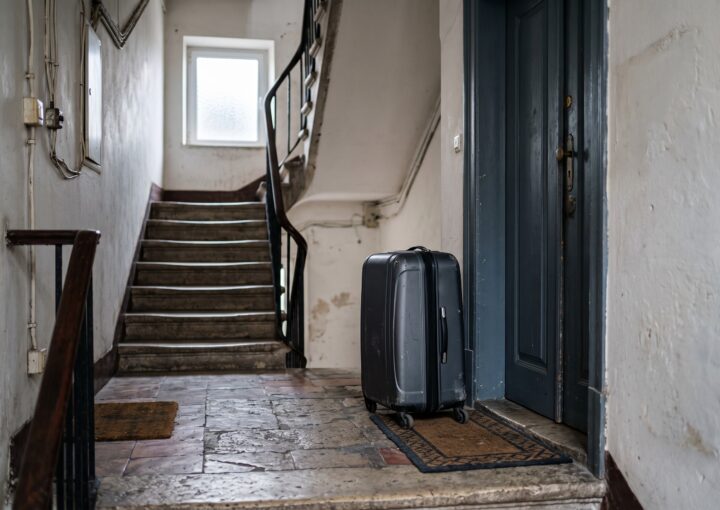 Mala de viagem no patamar de um prédio de habitação, junto à porta de uma fração