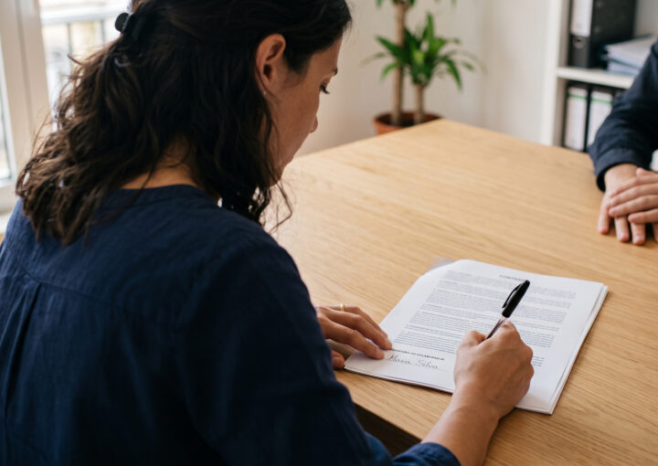 Trabalhadora a assinar um contrato de trabalho sem termo sobre a mesa de reuniões