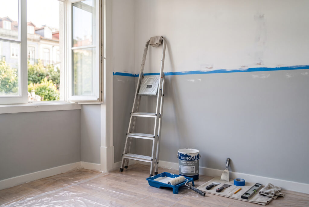 Escadote, tinta e ferramentas numa sala em obras, a ilustrar quem paga as reparações na casa com usufruto
