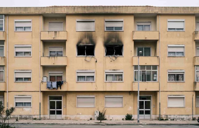 Fachada de um prédio de habitação com marcas de fuligem acima das janelas de um dos pisos