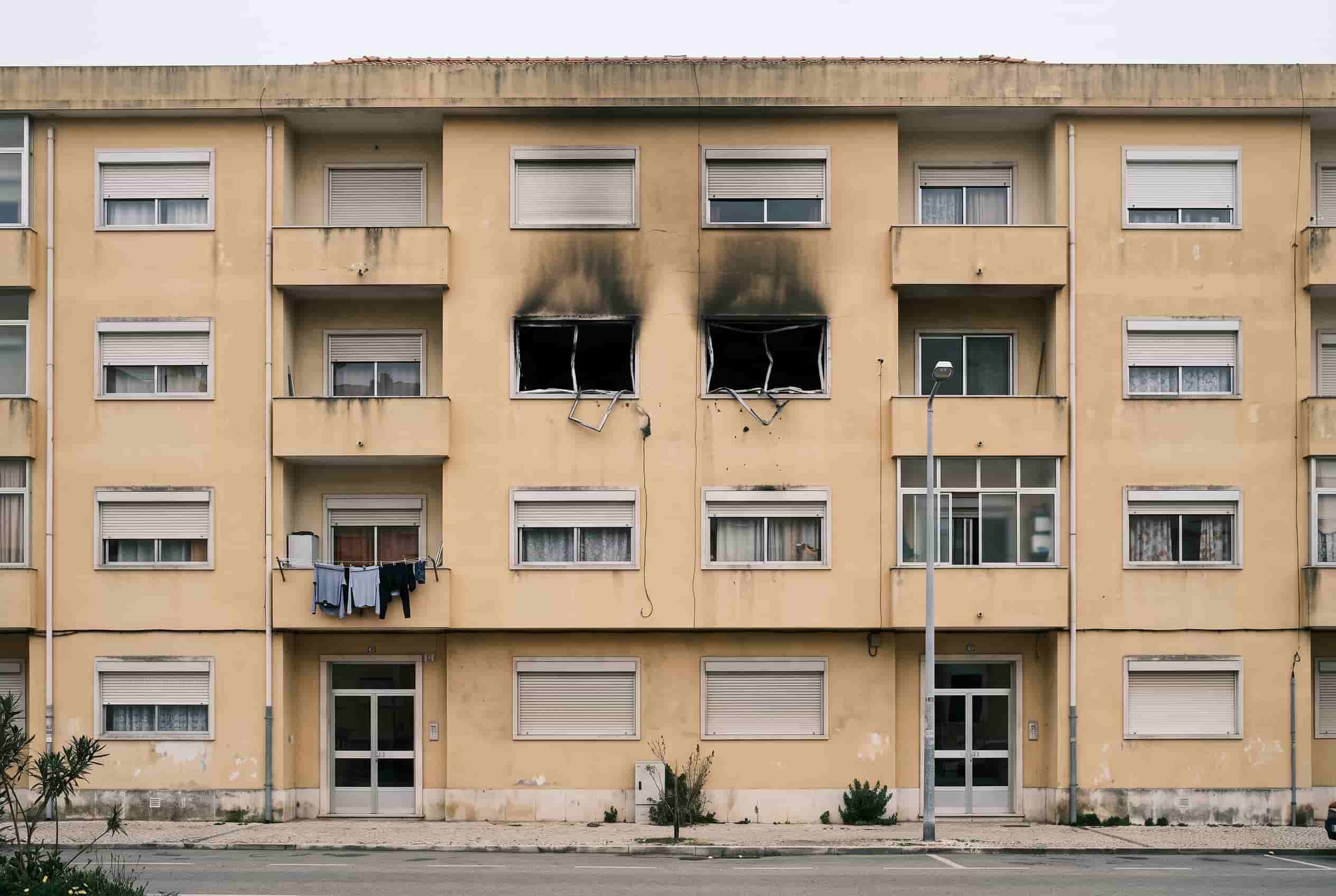 Fachada de um prédio de habitação com marcas de fuligem acima das janelas de um dos pisos