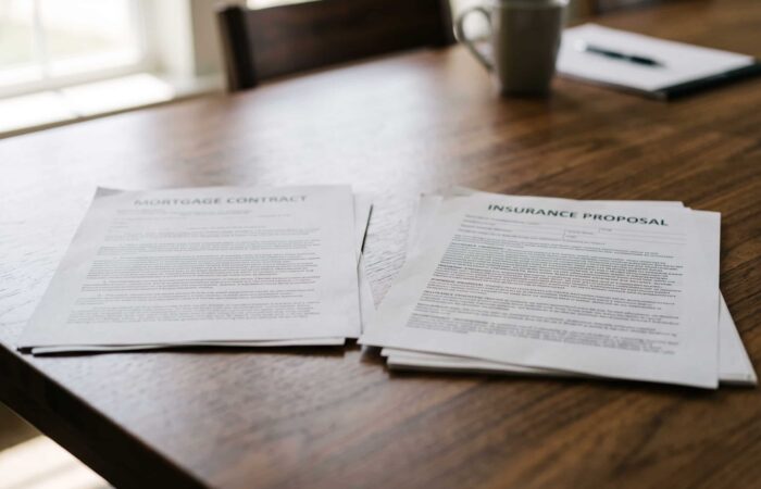 Contrato de crédito à habitação e proposta de seguro de vida sobre uma mesa de reunião.