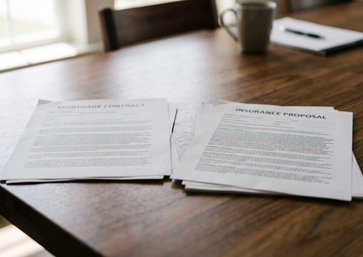 Contrato de crédito à habitação e proposta de seguro de vida sobre uma mesa de reunião.